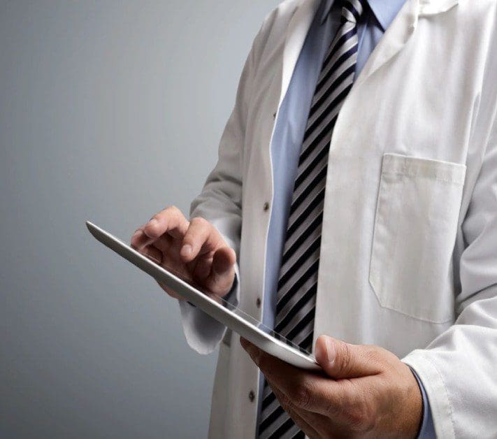 A doctor is holding his tablet in his hand.